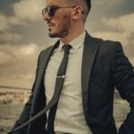 Elegant man in a suit with sunglasses standing by the Bosphorus in Istanbul, exuding confidence and style.