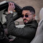 Confident man in a cabriolet wearing sunglasses and a suit, showcasing urban elegance.